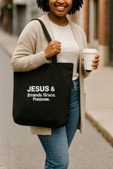 Person holding a black tote bag with text and a coffee cup on a city street.