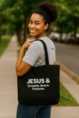 Woman carrying a black tote bag with Jesus & on a sidewalk